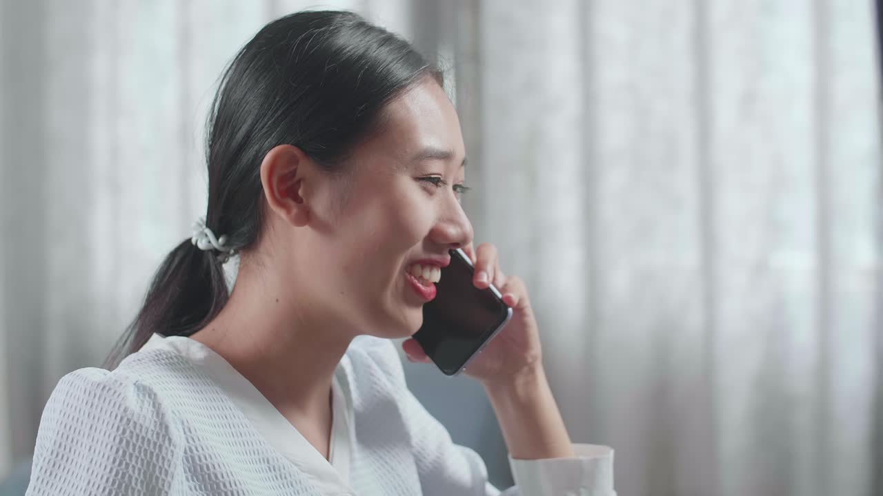 집에서 데스크에서 작업하는 동안 스마트폰으로 대화하는 하우스 모델과 함께 아시아 여성 엔지니어의 클로즈업