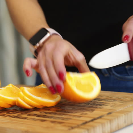 female hands cutting orange on a wooden board. woman in the kitchen. healthy eating. raw food. square video