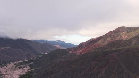 Drone-Elevándose-A-Las-Nubes-Mostrando-El-Paisaje-árido-Y-Montañoso-Del-Norte-De-Argentina,-Ruta-9,-Jujuy