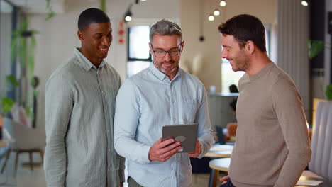 male multi-cultural business team with digital tablet in modern open plan office