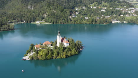 scenic view on bled lake with a church dedicated to the assumption of mary on a small island, julian alps, slovenia - aerial drone shot