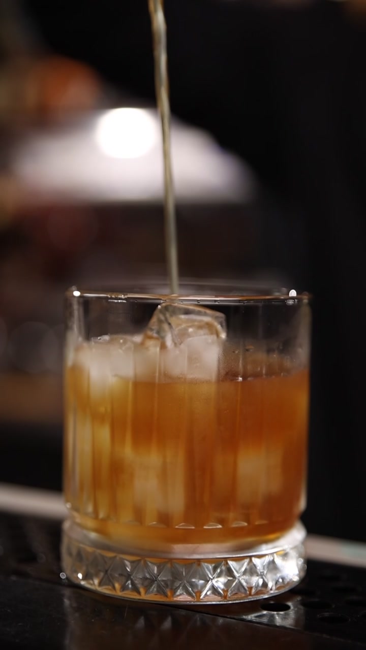 Primo piano di un cocktail versato in un bicchiere con ghiaccio