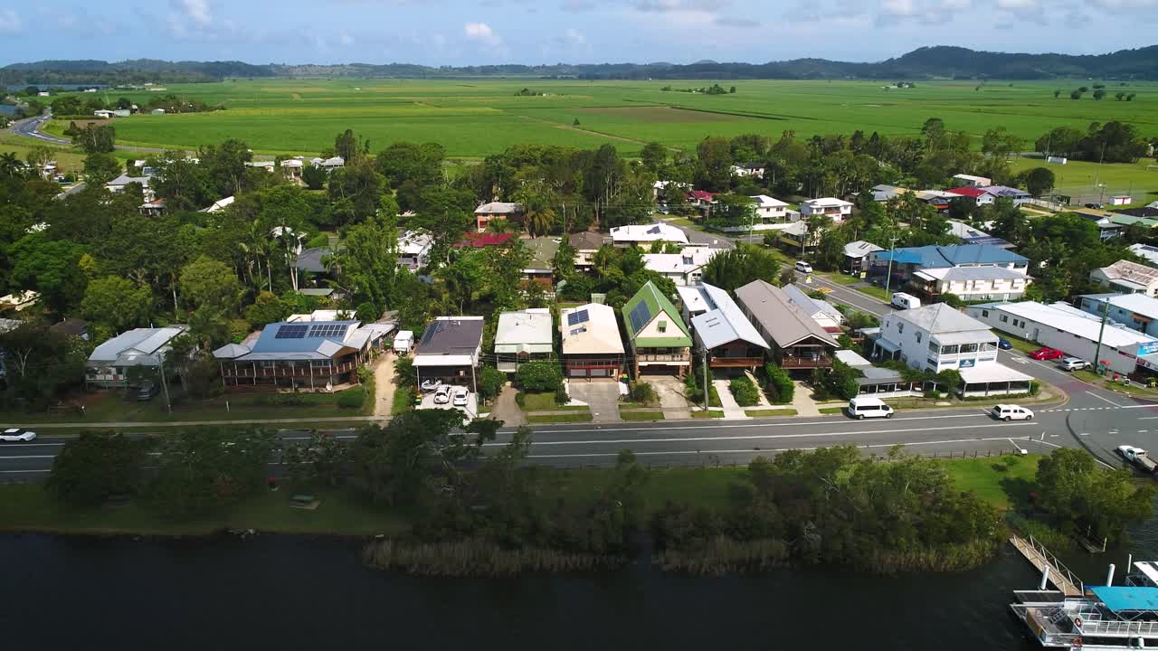 Right to left aerial view over Tumbulgum with farm land in the background, along the Tweed River, Northern New South Wales, Australia
