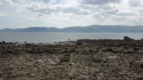 Strange-creepy-Martian-mountain-range-rocky-alien-stone-beach-coastline-low-right-slow