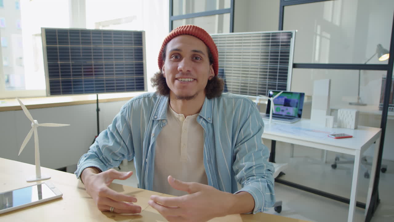 Giovane sviluppatore di energie rinnovabili parla alla telecamera in ufficio