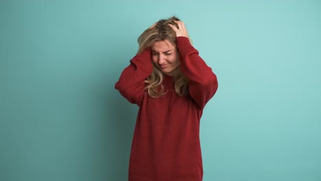 frustrated woman suffering from headache in blue studio
