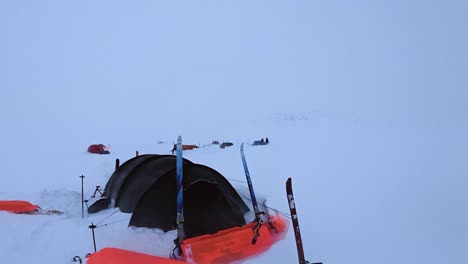 pan across snowy white winter camp scene with tents, skis, copy space
