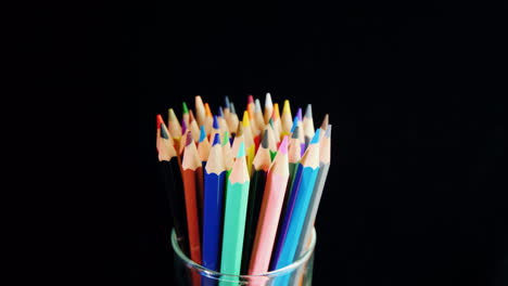 a set of multi-colored pencils on a black background