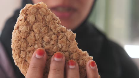 woman holding a half-eaten oatmeal cookie