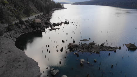 Drone-flying-over-beautiful-lake-with-dirt-road-ready-for-adventure