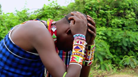 upset masai person in pain, hands on face, thinking bad thoughts, wearing traditional gear