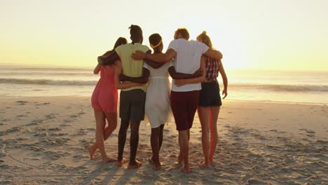 amigos adultos jóvenes relajándose en la playa al atardecer 4k