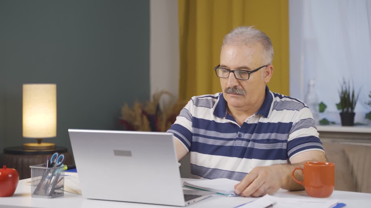 Home office worker old man working on laptop.