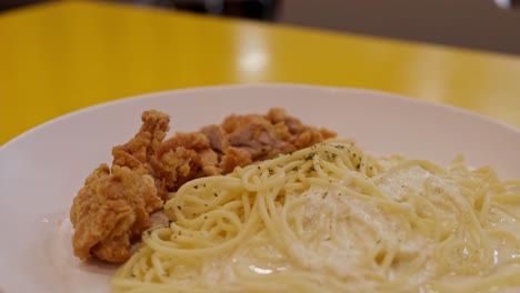 pedazos de pollo frito servidos con espagueti con salsa blanca y algunas especias, parece una deliciosa comida de carbonara