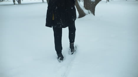 Woman-walking-outside-in-slow-motion-winter-snow-as-snowflakes-fall-in-cinematic-slow-motion