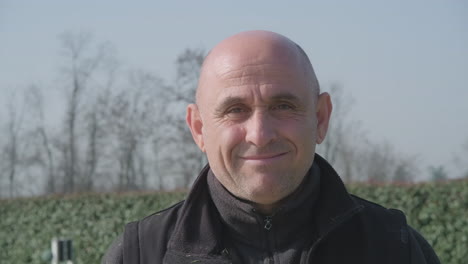 retrato de un hombre que mira hacia adelante y sonríe durante un hermoso día soleado en primavera - tiro estático medio en cámara lenta