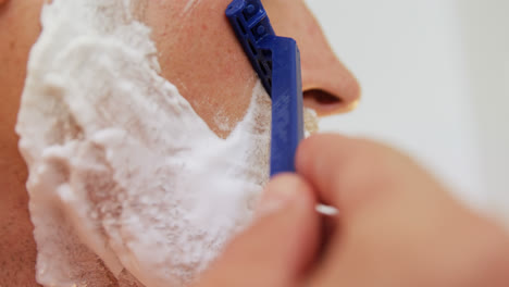 Young-man-shaving-his-face-with-razor-in-the-bathroom-4K-4k