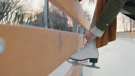 mujer atando patines de hielo en una pista de hielo al aire libre