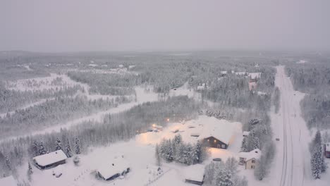 Snowy-Finland-neighborhood,-pine-forest-with-roads-and-cabins,-taiga-tundra-pull-back-drone-aerials
