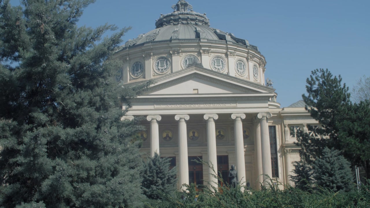 Tilt up shot of the athenium in Bucharest with vegetation in the foreground