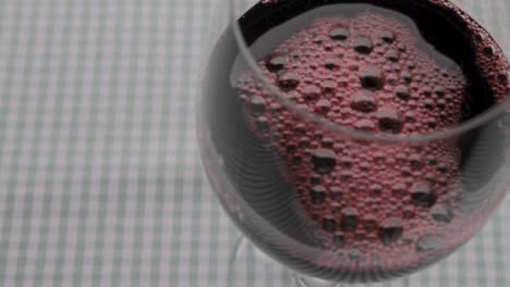 Red-wine-pouring-into-a-glass,-close-up,-gingham-tablecloth-backdrop