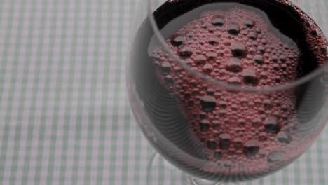 vino rojo vertiendo en un vaso, primer plano, telón de mesa de gingham