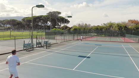 diverse male tennis players holding rackets and playing tennis at court