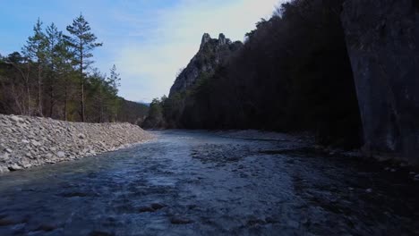 Aerial-shot-flying-over-the-river-in-the-spanish-pyrenees,-going-close-to-the-water-and-rocks