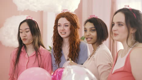 close up view of four  women with headdresses jumping and holding ballons while they wait for their friend to celebrate the bachelorette party