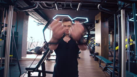athletic guy training muscles on a modern simulator. portrait of handsome sportsman in modern gym. athlete exercises hard concentrated working at his perfect body.