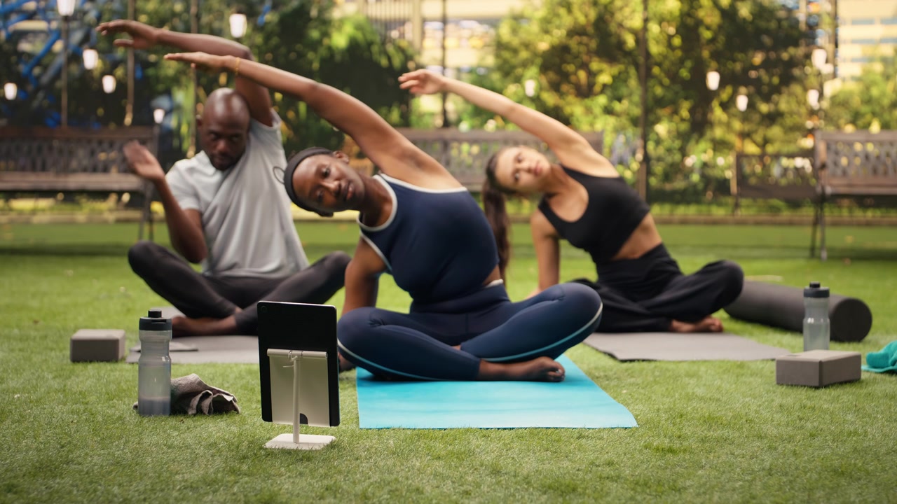 Giovane donna che esegue esercizi di stretching laterale davanti al laptop con amici