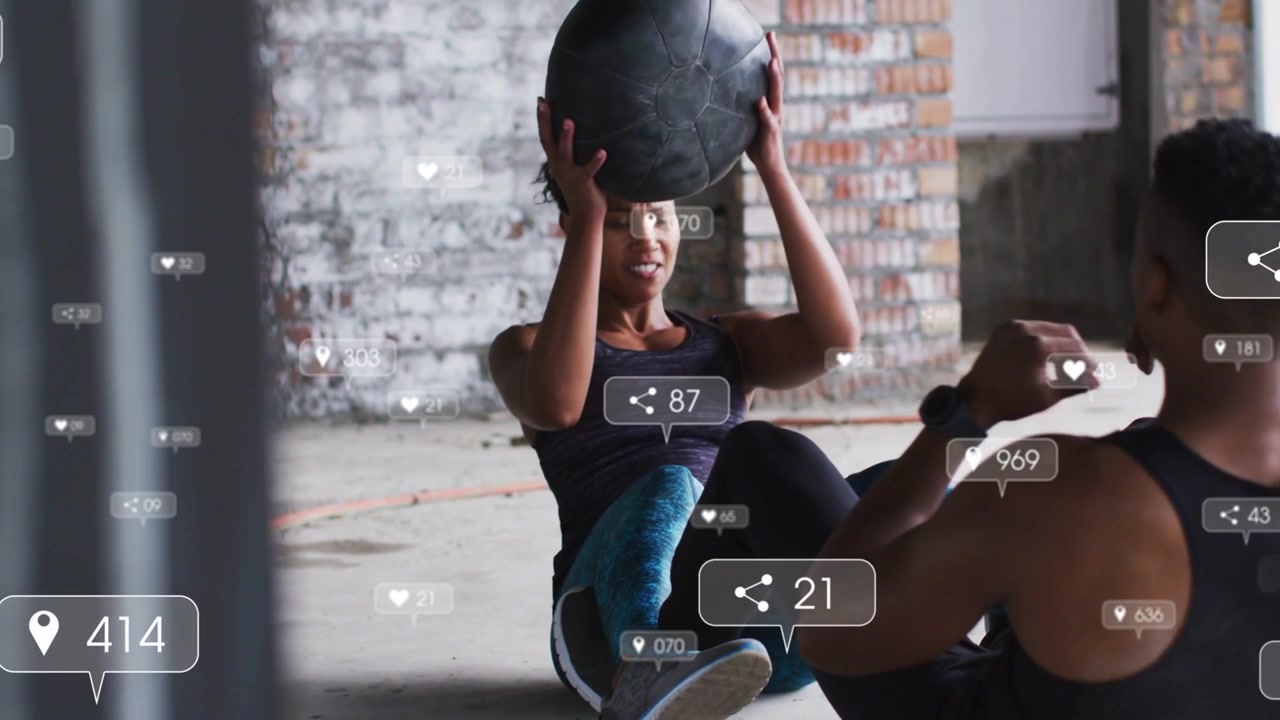 Vertical video: With left starting sit-up, pair passing med ball for core training, badges floating