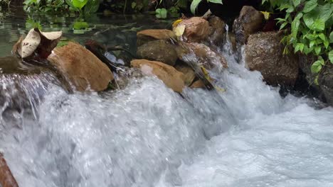 closeup of the gurgling stream of running water in kali umbul gumuk in magelang, indonesia, a river of clear springs showing the riverbed