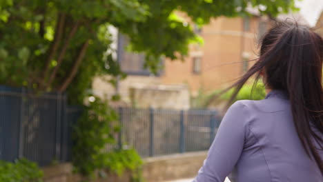 Rear-View-Of-Young-Woman-Exercising-Setting-Off-On-Run-Along-Urban-Street-Wearing-Wireless-Earbuds