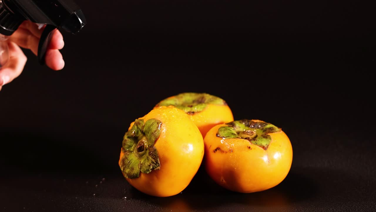 la niebla de agua sobre los persimones maduros en exhibición