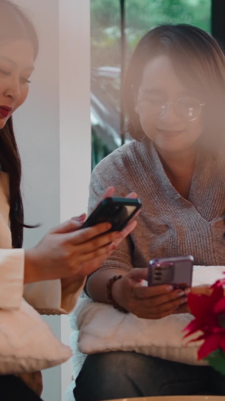 Two women using cellphones indoors