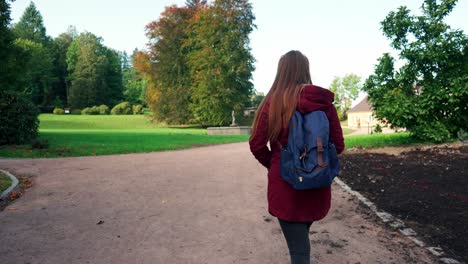 Kamerafahrt-Eines-Mädchens-Mit-Blauem-Rucksack,-Das-Durch-Einen-Wunderschönen-Grünen-Park-Spaziert