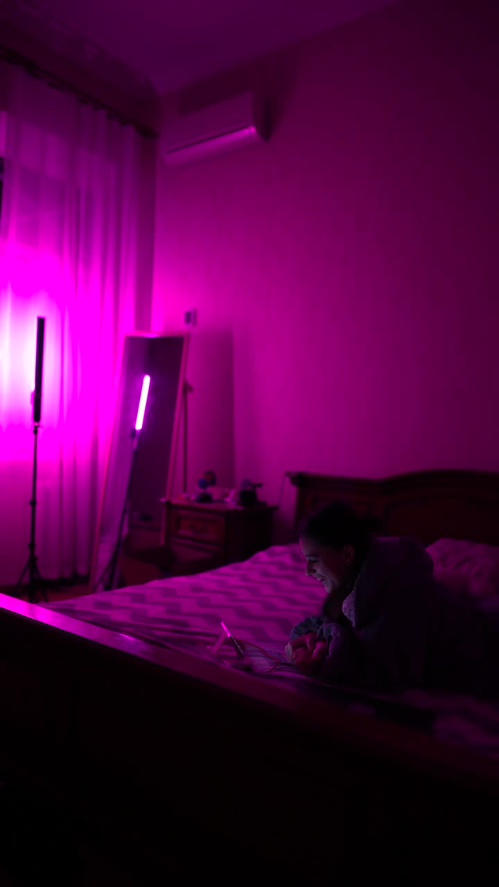 mujer usando tableta en un dormitorio iluminado de púrpura