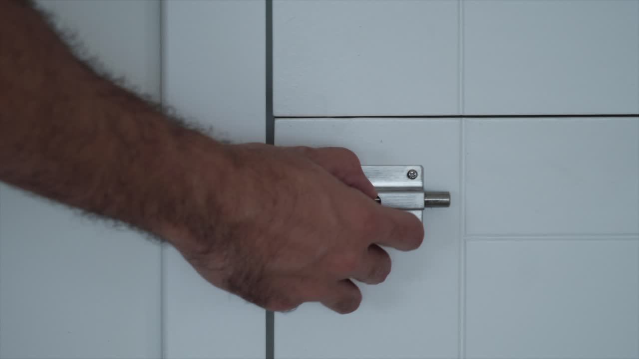 Man's hand locking a bathroom door in slow motion