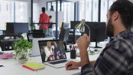 hombre de oriente medio teniendo una videollamada con colegas masculinos y femeninos en una computadora portátil en la oficina