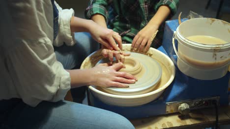 mom and child together make a vase on a pottery wheel