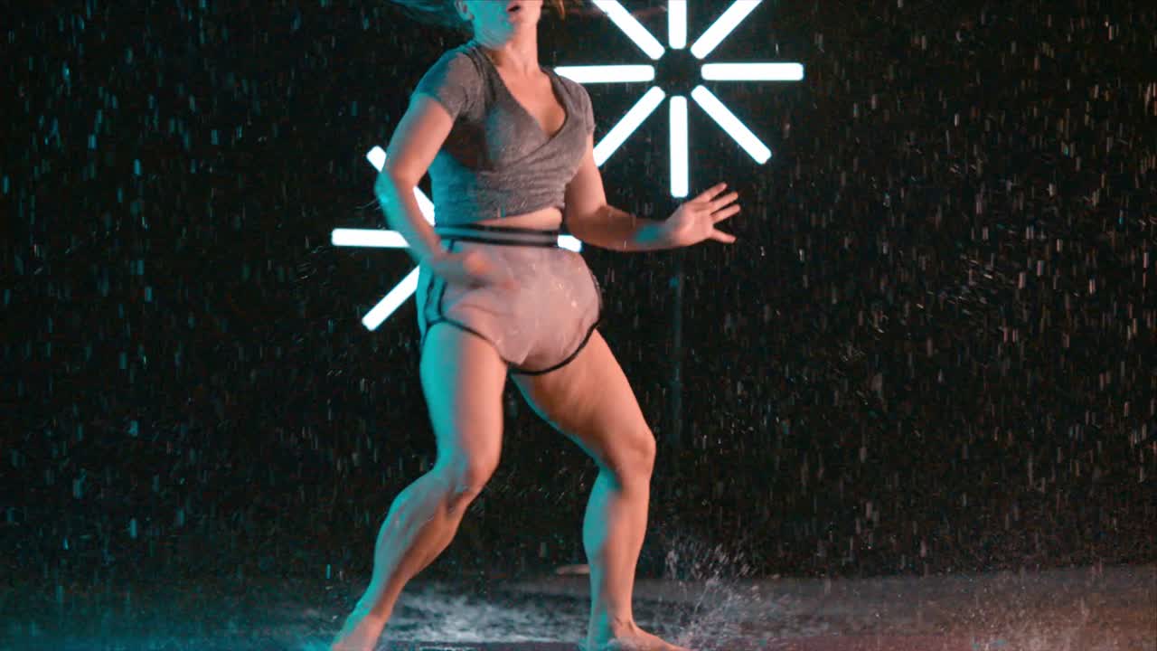 Pretty caucasian female dancer spinning in the rain, modern dance