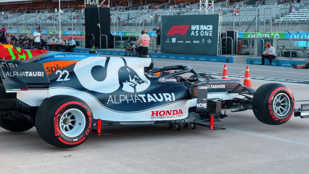 Austin, AS, 1 Agustus 2022: Mobil balap roda terbuka profesional di paddock. Tampilan samping mobil balap biru dan putih yang diparkir di aspal dengan branding tim dan detail aerodinamis.