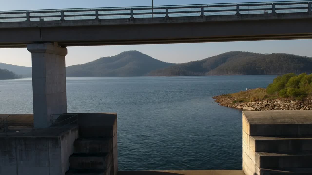 A unique perspective of scenic mountain waterway contained by large structured concrete dam.