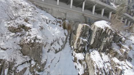 fast fly by of a mountain pass with a fast car driving inside a tunnel bridge surrounded by snow