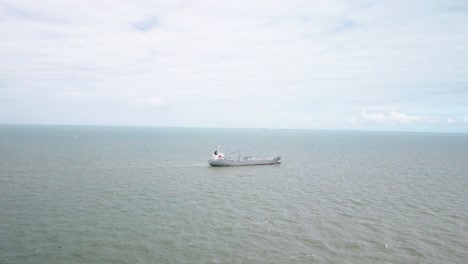 cargo ship in the middle of the sea with no other ships around cloudy day drone shot