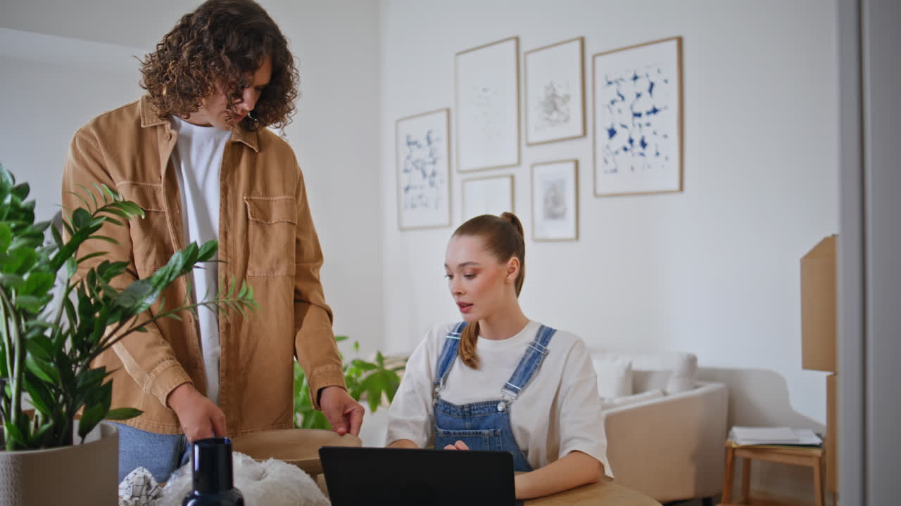 Skupiona kobieta pracuje na laptopie w nowoczesnym domu. Kobieta otoczona kartonami przeprowadzkowymi