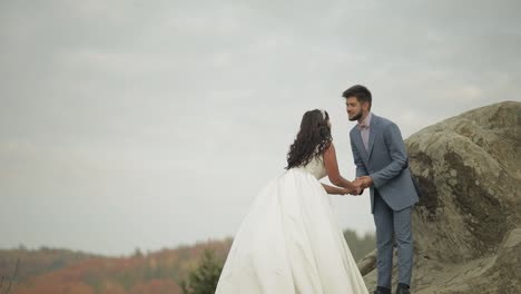 Newlyweds-stand-on-a-high-slope-of-the-mountain.-Groom-and-bride