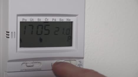 setting higher heating thermostat temperature on digital display, closeup view