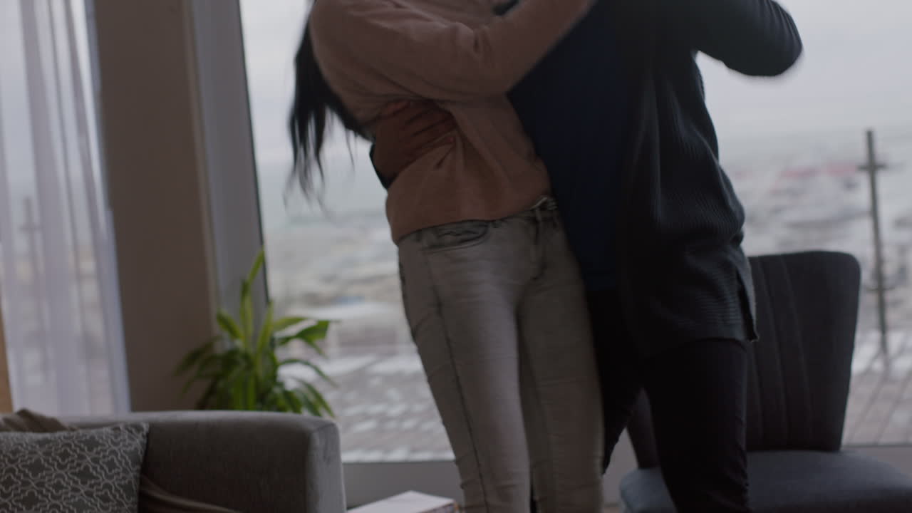 행복한 젊은 커플이 집에서 춤을 추고 성공적인 휴가를 즐기고 즐겁게 휴일에 라이프 스타일을 축하하고 거실에서 유쾌한 춤을 추고 있습니다.